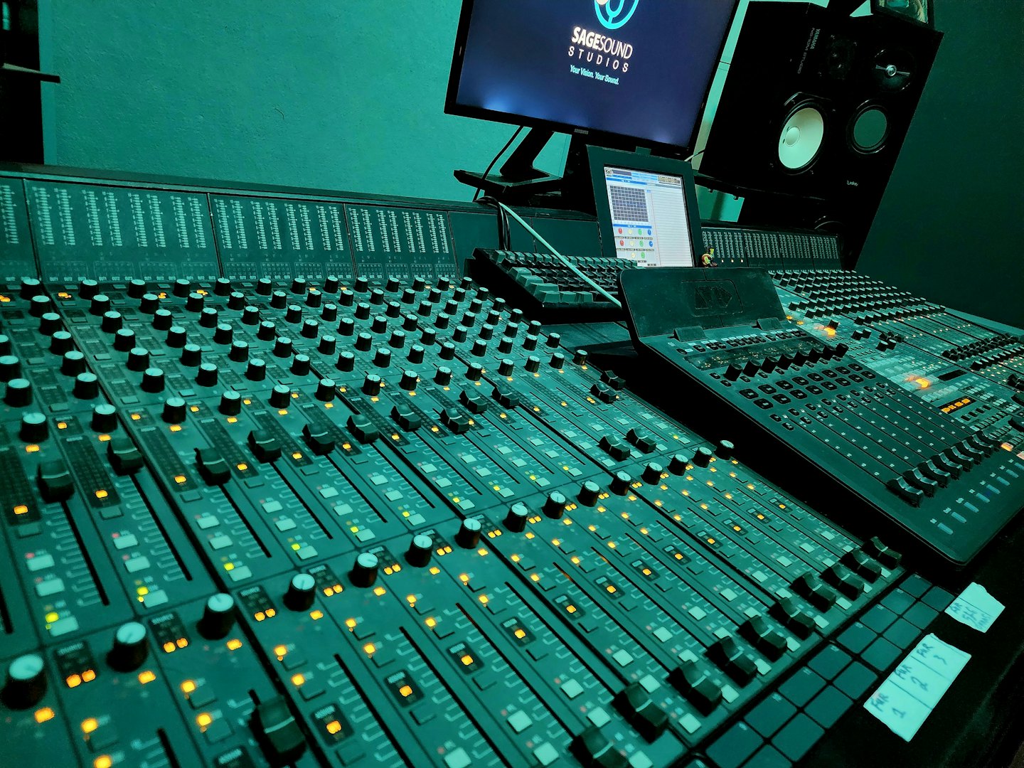 Consola de mezcla de audio con faders y perillas iluminados en un estudio.