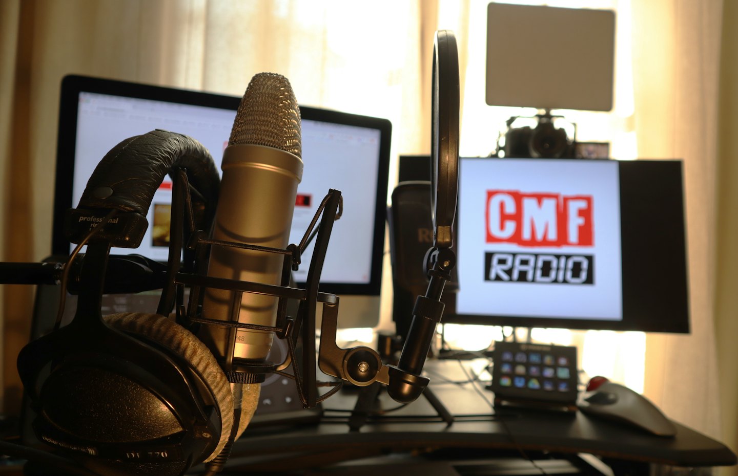 Micrófono de podcast con filtro anti-pop y auriculares sobre un escritorio.